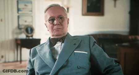 A Man Wearing A Suit And Bow Tie Looks At The Camera GIF