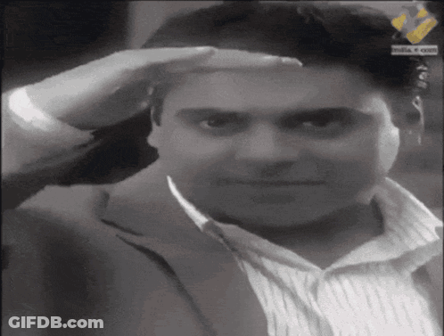 A Man Wearing A Suit And Striped Shirt Salutes With His Hand On His Forehead GIF