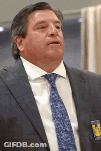 A Man Wearing A Suit And Tie Has A Badge On His Chest That Says Tigres GIF