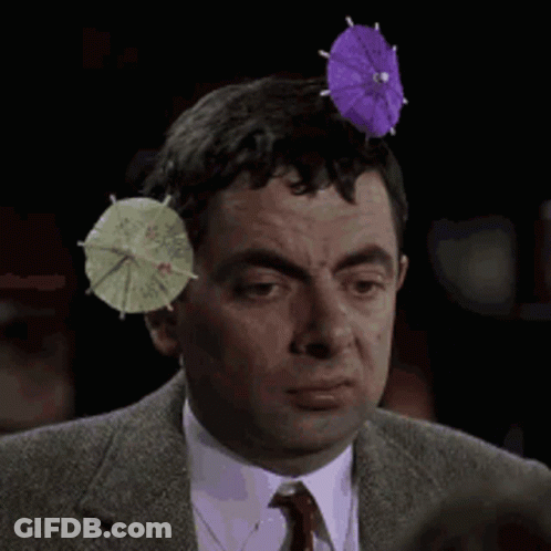 A Man Wearing A Suit And Tie Has Two Small Umbrellas On His Head GIF