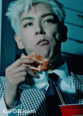 A Man Wearing A Suit And Tie Is Eating A Hamburger GIF
