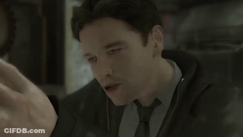 A Man Wearing A Suit And Tie Is Looking At Something GIF