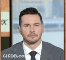 A Man Wearing A Suit And Tie Is Looking At The Camera . GIF