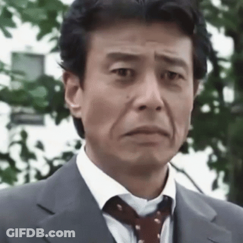 A Man Wearing A Suit And Tie Is Making A Funny Face . GIF