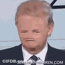 A Man Wearing A Suit And Tie Is Making A Funny Face . GIF
