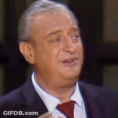 A Man Wearing A Suit And Tie Is Smiling GIF