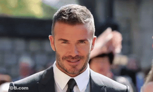 A Man Wearing A Suit And Tie Is Smiling For The Camera GIF