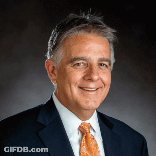 A Man Wearing A Suit And Tie Is Smiling For The Camera GIF