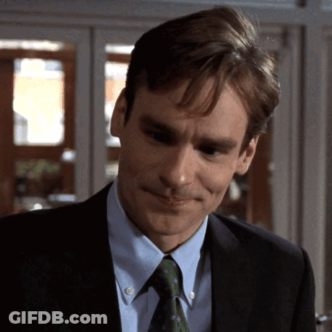 A Man Wearing A Suit And Tie Is Smiling GIF