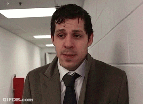 A Man Wearing A Suit And Tie Is Standing In A Hallway GIF