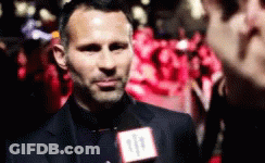 A Man Wearing A Suit And Tie Is Talking Into A Microphone With The Number 11 On It GIF