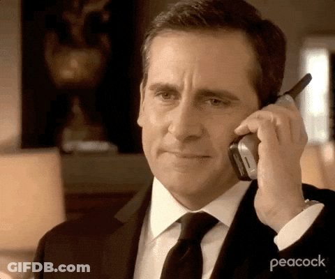 A Man Wearing A Suit And Tie Is Talking On A Cell Phone . GIF