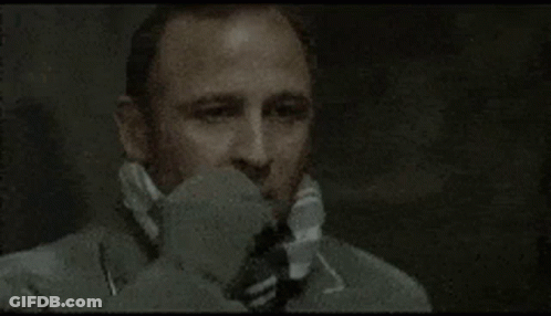 A Man Wearing A Suit And Tie Is Talking On A Telephone . GIF