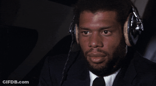 A Man Wearing A Suit And Tie Is Wearing Headphones GIF