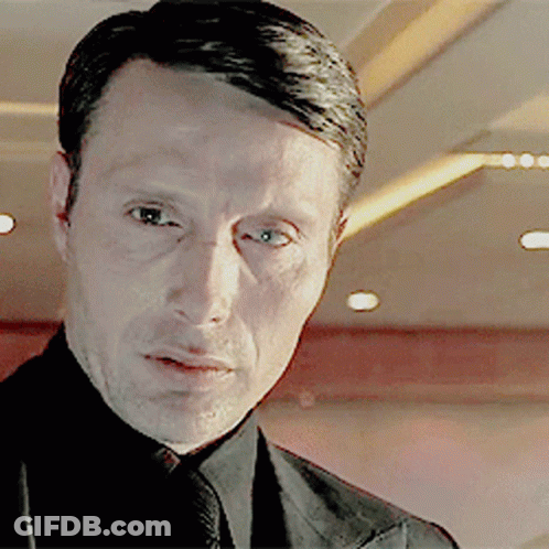 A Man Wearing A Suit And Tie Looks At The Camera GIF