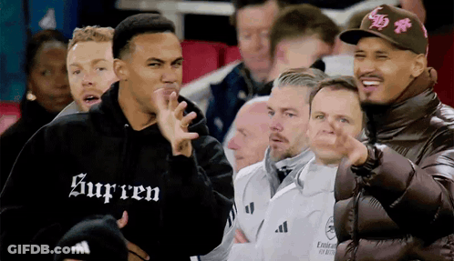 A Man Wearing A Supreme Hoodie Is Pointing At Something GIF