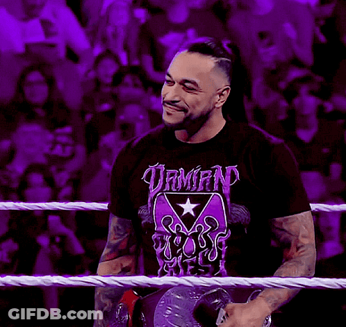 A Man Wearing A T-Shirt That Says Demon Reigns Stands In A Wrestling Ring GIF