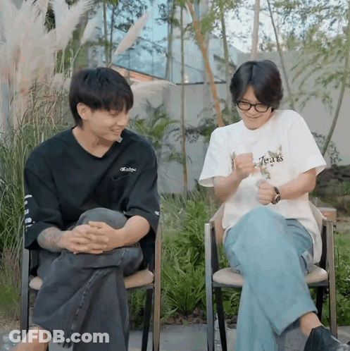 A Man Wearing A T-Shirt That Says Tears Sits Next To Another Man In A Chair GIF