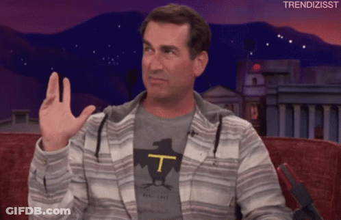 A Man Wearing A T-Shirt With The Letter T On It Waves His Hand GIF