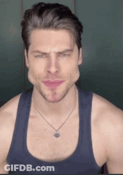 A Man Wearing A Tank Top And A Necklace Is Making A Face . GIF