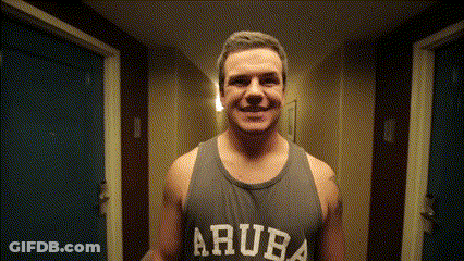 A Man Wearing A Tank Top That Says Aruba Smiles In A Hallway GIF