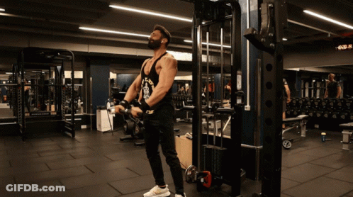 A Man Wearing A Tank Top That Says Los Angeles Is Lifting Weights In A Gym GIF