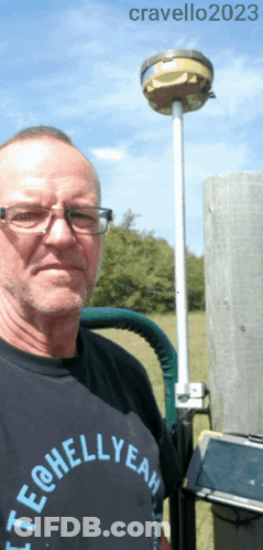 A Man Wearing A Tech @ Hellyeah Shirt Stands In Front Of A Pole GIF