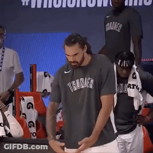 A Man Wearing A Thunder T-Shirt Is Standing Next To Another Man . GIF