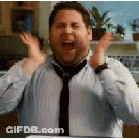A Man Wearing A Tie And A Blue Shirt Is Making A Funny Face . GIF