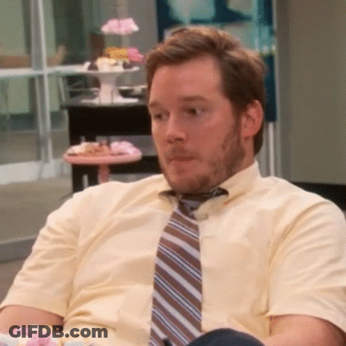 A Man Wearing A Tie And A Yellow Shirt Is Sitting In A Chair GIF
