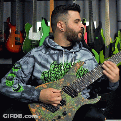 A Man Wearing A Tie Dye Hoodie Playing A Guitar GIF