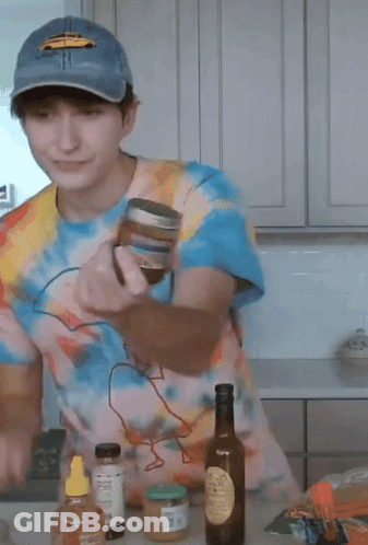 A Man Wearing A Tie Dye Shirt And A Blue Hat Is Standing In A Kitchen GIF