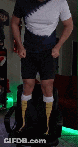 A Man Wearing A Tie Dye Shirt And Shorts Is Standing On A Chair GIF