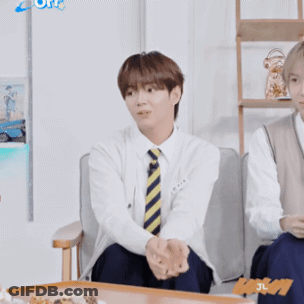 A Man Wearing A Tie Is Sitting In A Chair GIF
