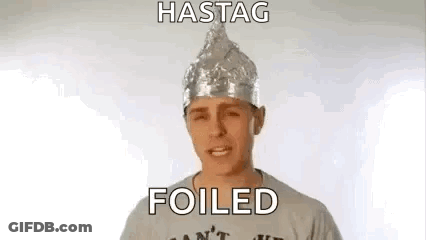 A Man Wearing A Tin Foil Hat And A T-Shirt Is Making A Funny Face . GIF