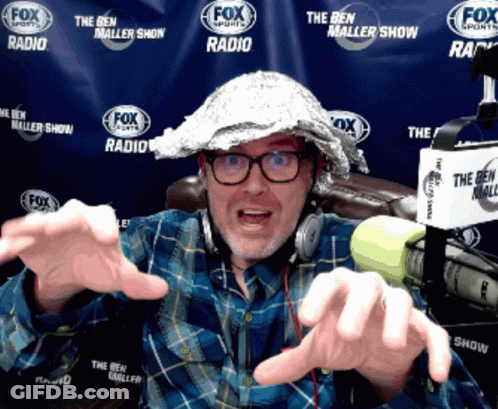A Man Wearing A Tin Foil Hat And Headphones Is In Front Of A Fox Sports Banner GIF
