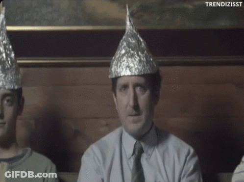 A Man Wearing A Tin Foil Hat Is Sitting Next To Two Other People GIF
