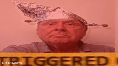 A Man Wearing A Tin Foil Hat Is Standing In Front Of A Yellow Sign That Says Triggered GIF
