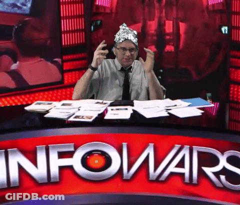 A Man Wearing A Tin Foil Hat Sits At A Desk In Front Of A Sign That Says Info Wars GIF