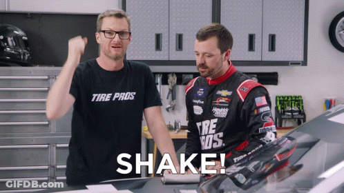 A Man Wearing A Tire Pro Shirt Stands Next To Another Man GIF