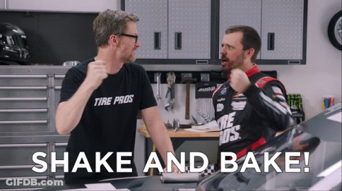 A Man Wearing A Tire Pros Shirt Stands Next To Another Man In A Garage GIF