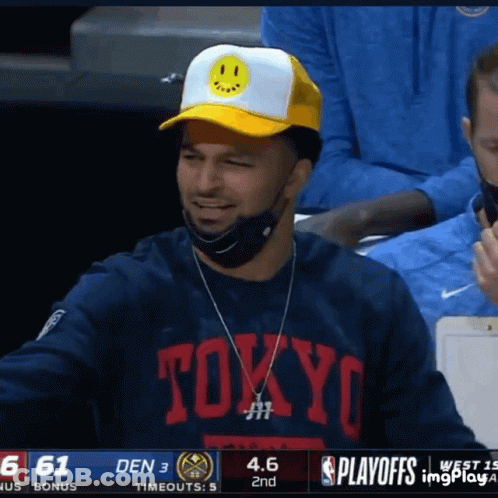 A Man Wearing A Tokyo Shirt And A Yellow Hat Smiles During A Basketball Game GIF