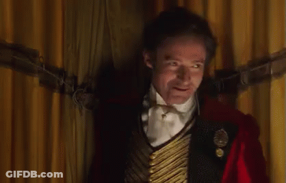 A Man Wearing A Top Hat And A Red Jacket Is Standing In Front Of A Crowd . GIF
