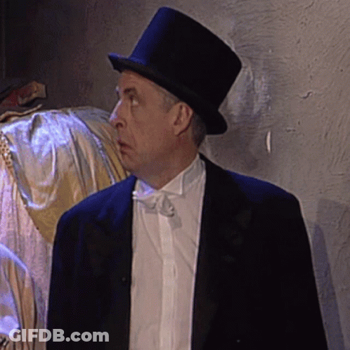 A Man Wearing A Top Hat And A Tuxedo Looks To The Side GIF