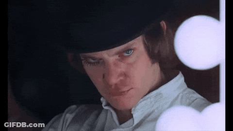 A Man Wearing A Top Hat And A White Shirt Looks At The Camera GIF