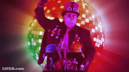 A Man Wearing A Top Hat And Glasses Is Standing In Front Of A Disco Ball GIF