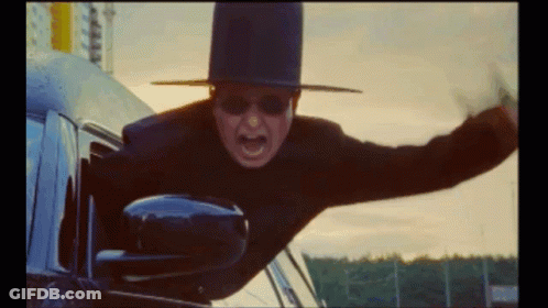 A Man Wearing A Top Hat And Sunglasses Is Flying Out Of A Car Window GIF