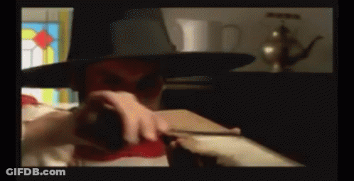 A Man Wearing A Top Hat Is Holding A Red Object GIF