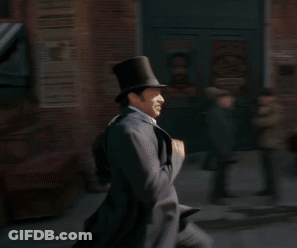 A Man Wearing A Top Hat Is Running Down A Street GIF