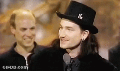 A Man Wearing A Top Hat Is Talking Into A Microphone . GIF